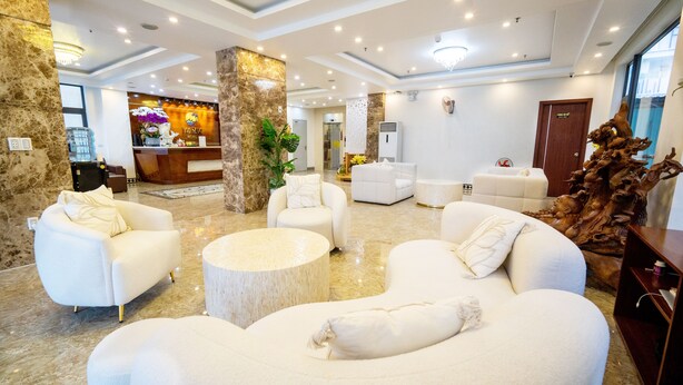 A spacious lobby with white sofas, a reception desk, and a large wooden sculpture. - Dao Ngoc Hotel (Da Nang)