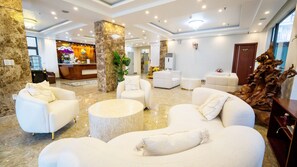Un vestíbulo espacioso con sofás blancos, una recepción y una gran escultura de madera.