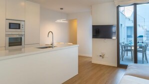 Cozinha moderna com eletrodomésticos embutidos, uma ilha central com pia e uma área de refeições com vista para o exterior.