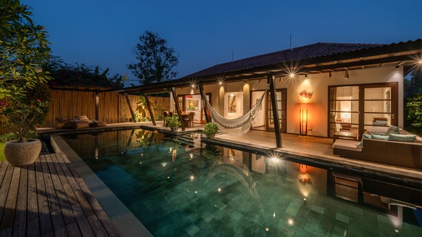 A modern poolside area with a hammock, outdoor seating, and a well-lit patio. - Villa Claudia  (Kerobokan)