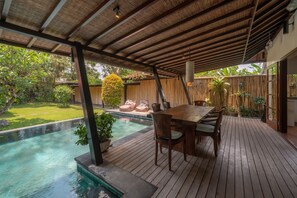 Una terraza de madera con piscina, una mesa y sillas.