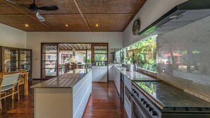 A modern kitchen with a wooden ceiling, a central island, and a view of the outdoors. - Villa Claudia  (Kerobokan)