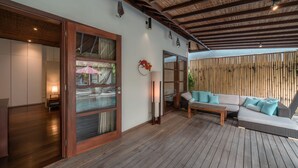 A modern interior with a wooden floor, a sofa set, and a glass door leading to a balcony. - Villa Claudia  (Kerobokan)