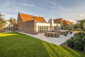 A house with a patio area, a dining set, and a well-maintained lawn. - The Beach House (B), Brancaster, Norfolk (Brancaster)