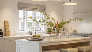 Una cocina moderna con una isla grande, armarios blancos y un ventanal con vistas.
