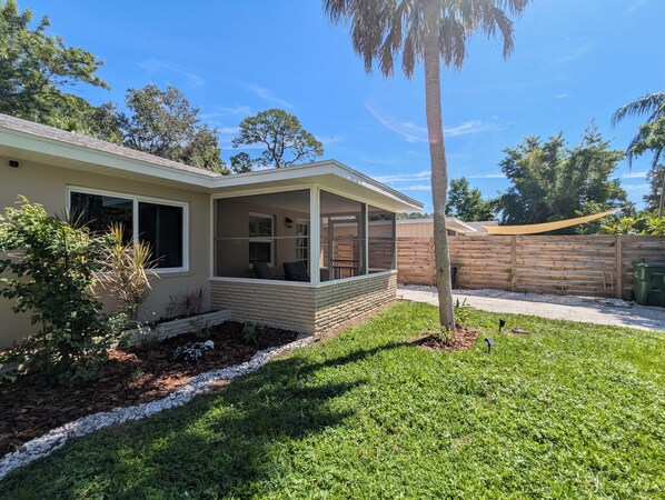 A single-story house with a covered porch, a brick foundation, and a fenced backyard. - Downtown Home! Spacious Backyard, King Size Bed, Fully Equipped Near Beaches (Sarasota)