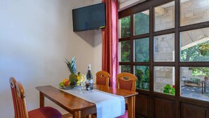 Un coin repas avec une table dressée pour deux personnes, une bouteille de vin et un panier de fruits.