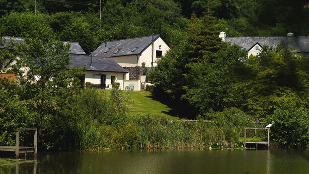 Une maison au bord du lac, avec une pelouse et un quai.
