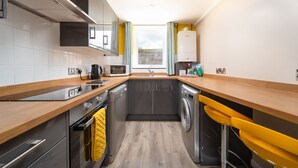 A compact kitchen with a microwave, kettle, and washing machine. - Smithy Cottage at Lower Aylescott (West Down)