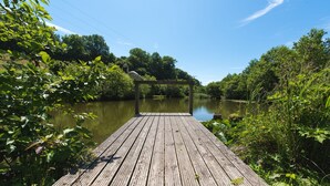 A wooden dock extending into a calm river surrounded by lush greenery. - Smithy Cottage at Lower Aylescott (West Down)