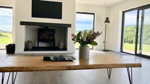 En moderne stue med pejs, et træbord og en blomstervase.