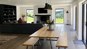 En moderne stue med et træspisebord, en mørk sofa og et tv ophængt på væggen.