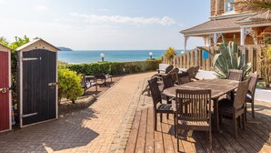 A patio with wooden furniture and a view of the sea. - 8 Hartland, sleeps 6 with sea view (Esplande, Woolacombe)