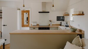 A modern kitchen with a central island, wooden countertops, and pendant lighting.