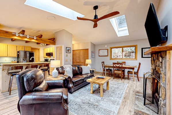 A spacious living room with a leather sofa, wooden coffee table, and a dining area.