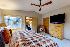 A bedroom with a bed, a television, a dresser, a chair, and a window.