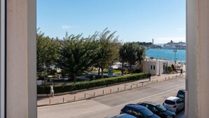 A coastal view with parked cars, a pedestrian path, and a body of water in the background. - Lara's House by Interhome (Split)