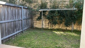A backyard with a wooden fence, a pergola, and a stone wall. - Stylish Retreat in Macquarie Links - Golf, Comfort & Tranquility (Macquarie Links)