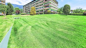 A multi-story hotel with a green lawn in front, benches, and a clear sky. - Seezugang & Ski Ossiacher See by Interhome (Bodensdorf)