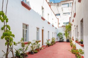 Stroll through this traditional corridor lined with lush greenery and red accents.