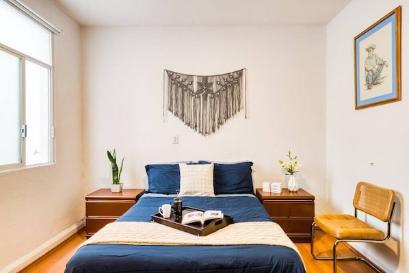 Relax in this serene bedroom with a large bed, decorative wall hanging, and a cozy reading nook.