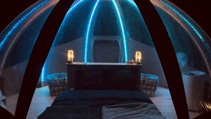A dome-shaped room with a central table and two lamps, illuminated by blue LED lights along the dome's edges. - Starry Wigwam (pets not allowed) (MESSEY SUR GROSNE)
