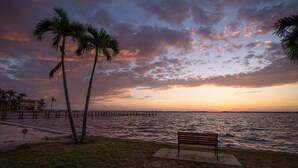 A bench by the water with palm trees and a pier in the background. - 1449 Braman Ave (Fort Myers)