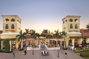 A shopping plaza with a central fountain, surrounded by palm trees and various storefronts including a flatbread and a garage. - 1449 Braman Ave (Fort Myers)