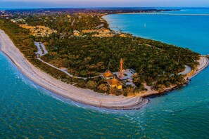 An aerial view of a coastal area with a lighthouse, clear blue waters, and a sandy beach. - 1449 Braman Ave (Fort Myers)
