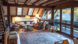 Un salon confortable avec une grande fenêtre, un ensemble de canapés, une table basse et un téléviseur.