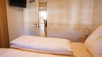A hotel room with a bed, a TV mounted on the wall, and a door leading to a hallway.