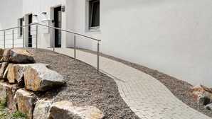 Un edificio con fachada blanca, barandilla metálica y camino pavimentado.