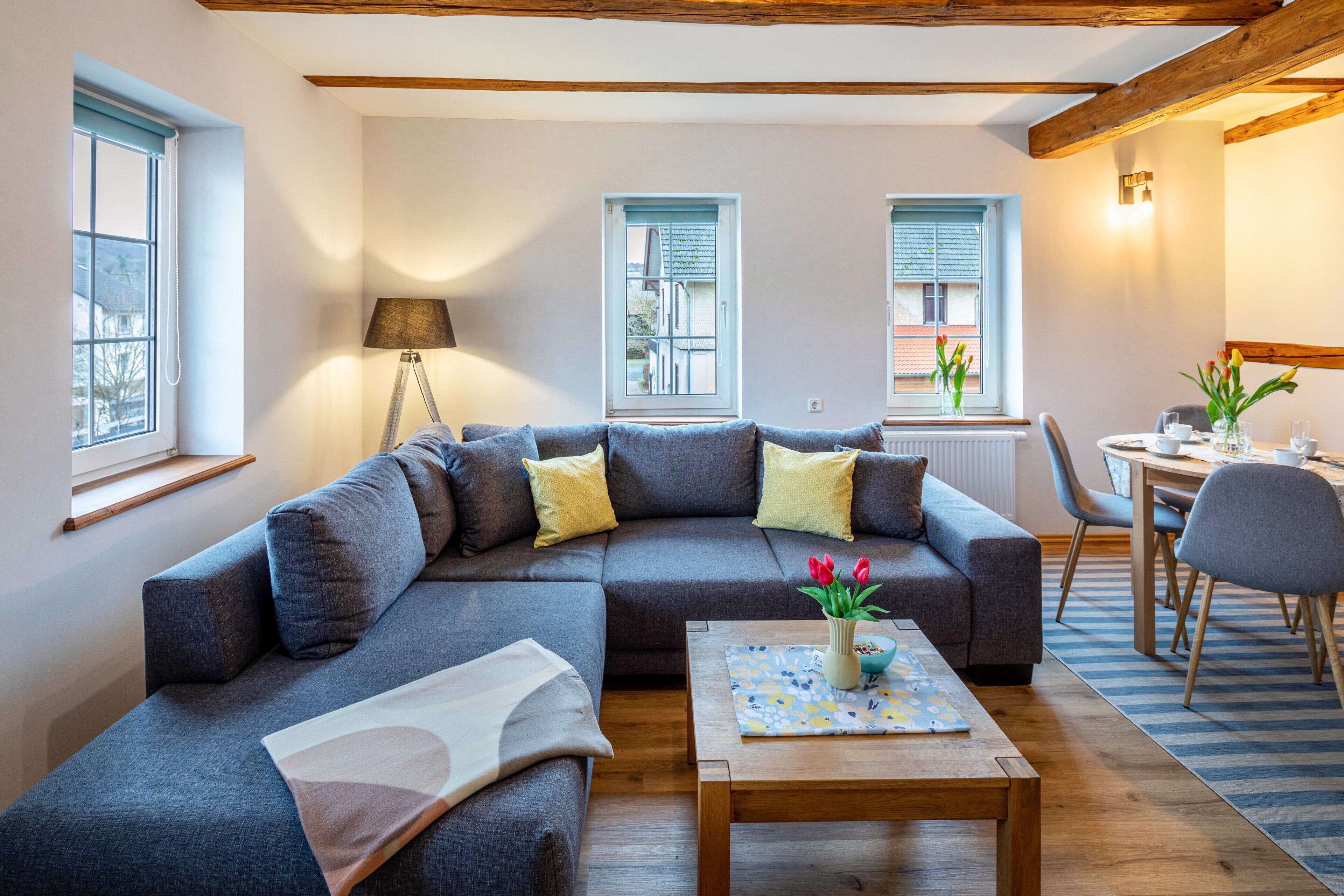 Ein modernes Wohnzimmer mit Ecksofa, Couchtisch und Essbereich mit Stühlen und Tisch.
