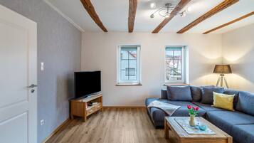 Ein Wohnzimmer mit Fernseher, Sofa und Couchtisch.
