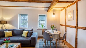 A cozy living room with a sofa, a dining table, and a lamp.