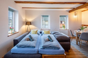 Une pièce comprenant un lit, un canapé, une table et deux fenêtres.