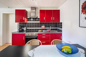 A kitchen with red cabinets, a black countertop, and a blue bowl with fruits on the table. - Apartment "Waldeckchen" with Private Terrace & Wi-Fi (Waldeck)