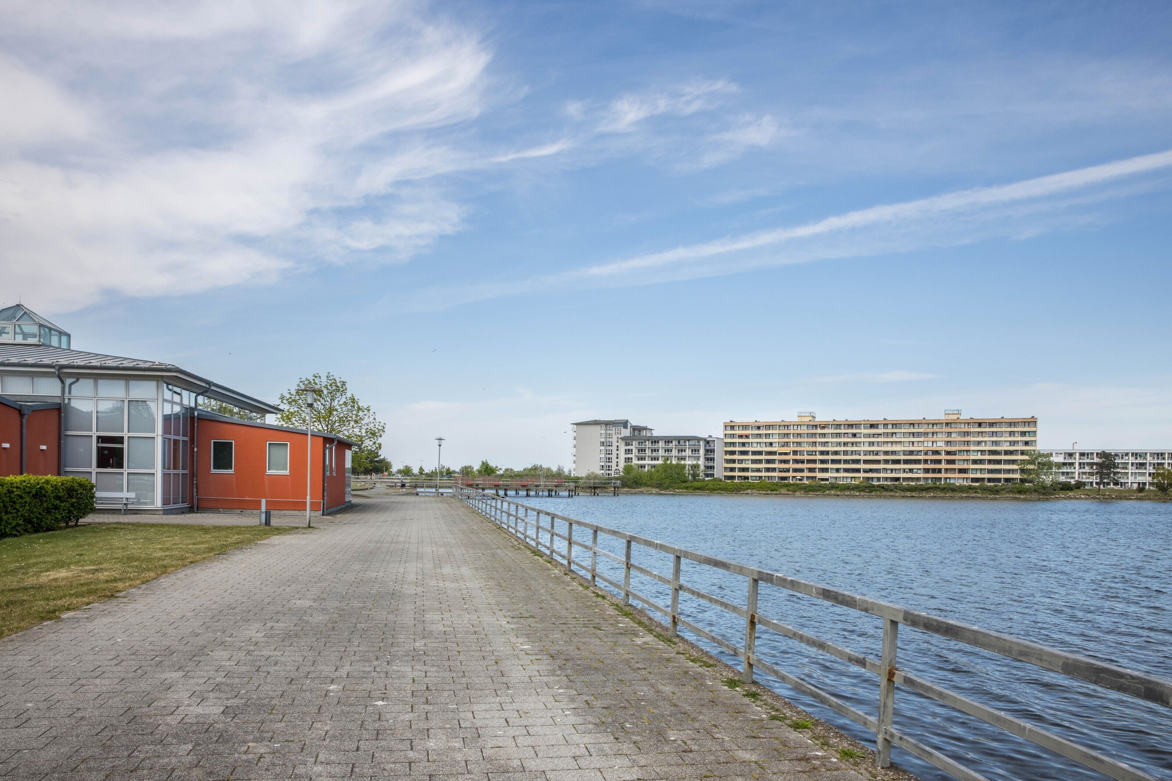 A waterfront walkway with a building on the left and a large apartment complex on the right.