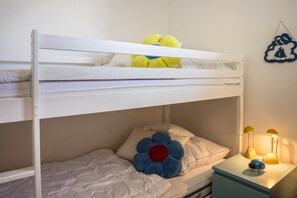 Una cama litera con una cama superior, una mesita de noche con lámpara y un adorno en la pared.