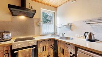 Una cocina con estufa, horno, pileta y ventana.