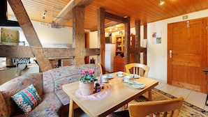 Ein Holzinterieur mit Esstisch, Stühlen, einer Couch und einer Küchenzeile.