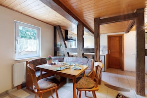 A dining area with a wooden table and chairs, a window, and a view of the outdoors.
