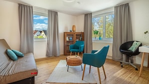 Una sala moderna con un sofá, dos sillones, una mesita y una estantería.