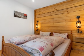 A double bed with floral bedding, wooden headboard, and wall-mounted light fixtures. - Apartment 'Ferienwohnung 1' with Mountain View, Shared Terrace and Wi-Fi (Haslach im Kinzigtal)