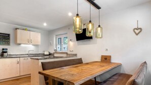 A modern kitchen with wooden cabinets, a wooden dining table, and hanging pendant lights. - Apartment 'Ferienwohnung 1' with Mountain View, Shared Terrace and Wi-Fi (Haslach im Kinzigtal)