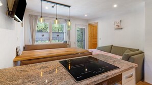 A modern kitchen with a built-in stove, wooden bench seating, pendant lighting, and a view of the outdoors. - Apartment 'Ferienwohnung 1' with Mountain View, Shared Terrace and Wi-Fi (Haslach im Kinzigtal)