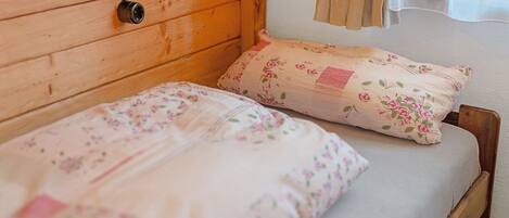 A wooden bed with floral bedding and a headboard with a light fixture.