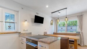 A modern kitchen with a built-in stove, a flat-screen TV, and pendant lights. - Apartment 'Ferienwohnung 1' with Mountain View, Shared Terrace and Wi-Fi (Haslach im Kinzigtal)