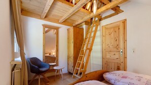 A bedroom with a wooden ladder, a chair, a small table, and a bed with floral bedding. - Apartment 'Ferienwohnung 2' with Mountain View, Shared Terrace and Wi-Fi (Haslach im Kinzigtal)