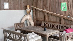 A wooden outdoor seating area with benches and a table, a decorative vase, and a sign on the wall. - Apartment 'Ferienwohnung 2' with Mountain View, Shared Terrace and Wi-Fi (Haslach im Kinzigtal)